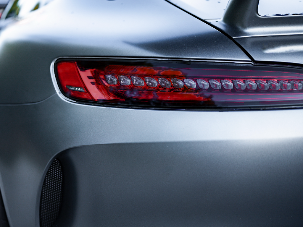Close-up of a sleek silver car tail light with a red LED strip and smooth body panel.