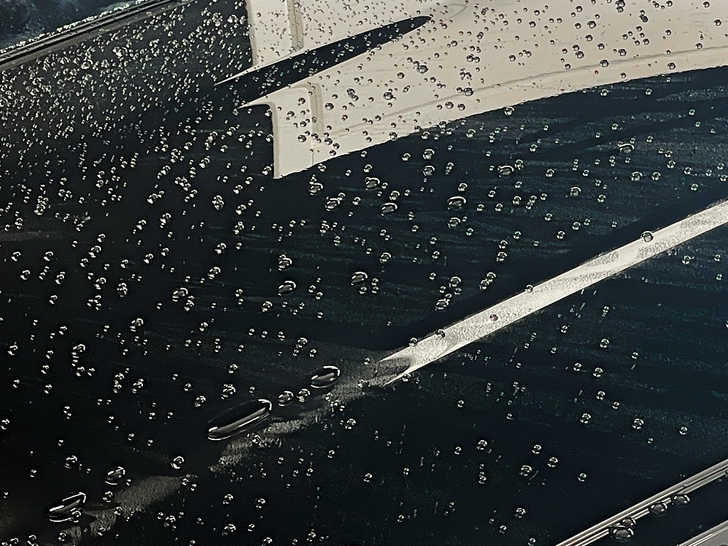 Pannello scuro dopo la pioggia: l'acqua si raccoglie in gocce distinte invece di stendersi, il comportamento di una superficie con il coating ancora attivo.